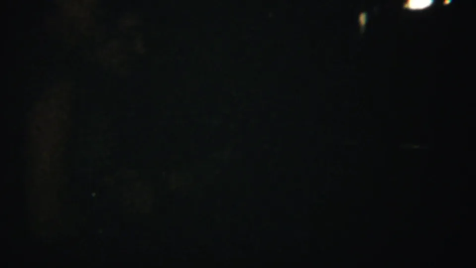 Underexposed 1951 8mm home-movie frame from the Westville reel, with faint grain and tiny light traces in darkness.