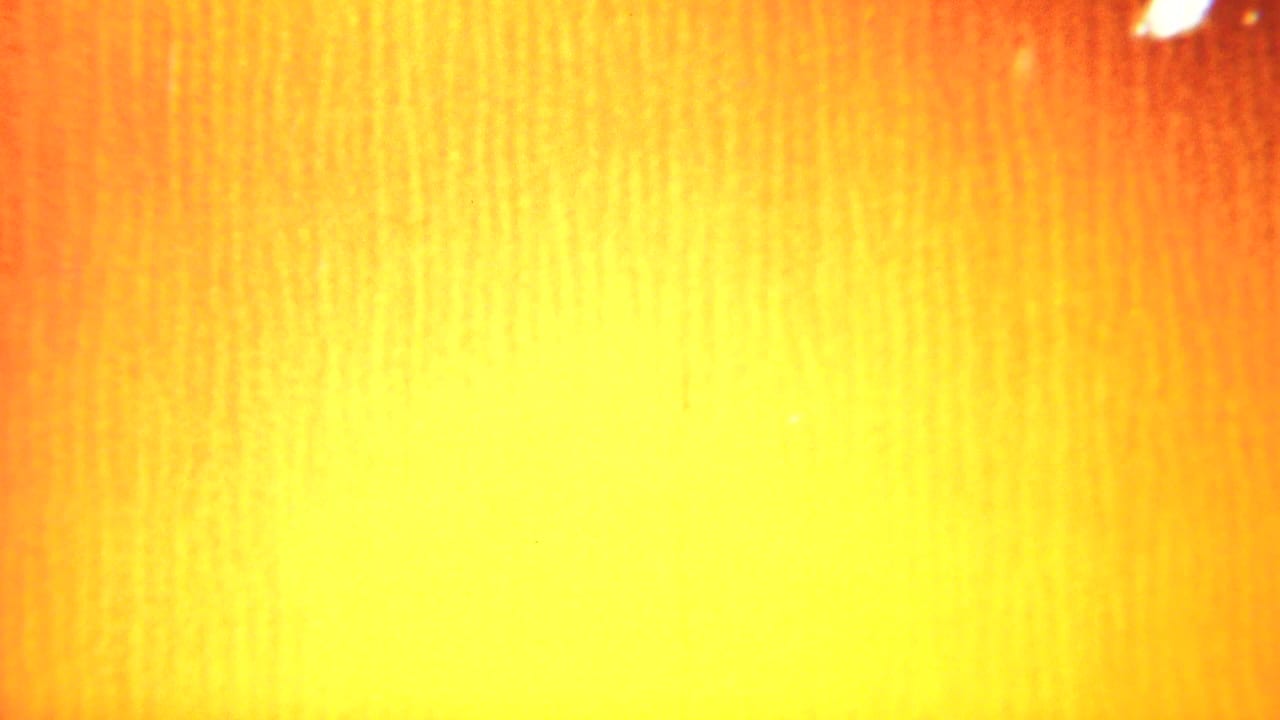 Bright yellow-orange flare fills the frame with vertical film texture.