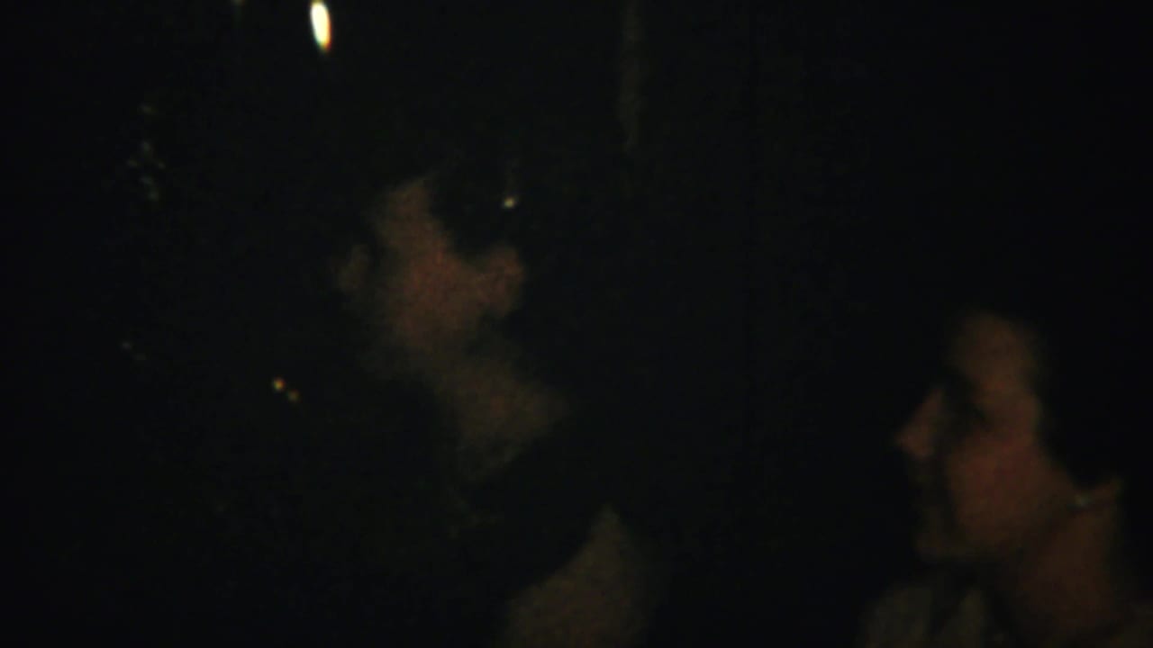 Dim interior with several adult faces gathered in close conversation.