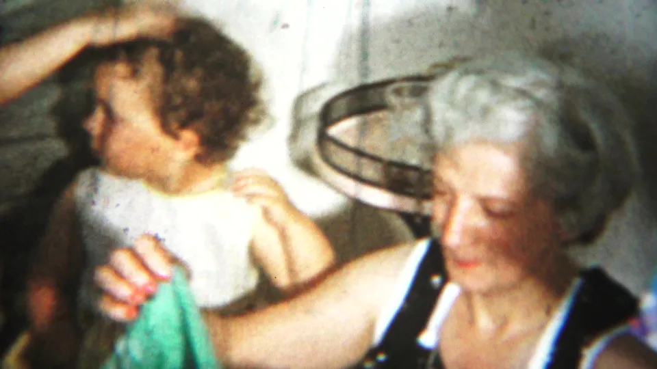 1951 Westville family footage showing two women indoors, including a light-haired woman in a sleeveless dark dress near the camera.