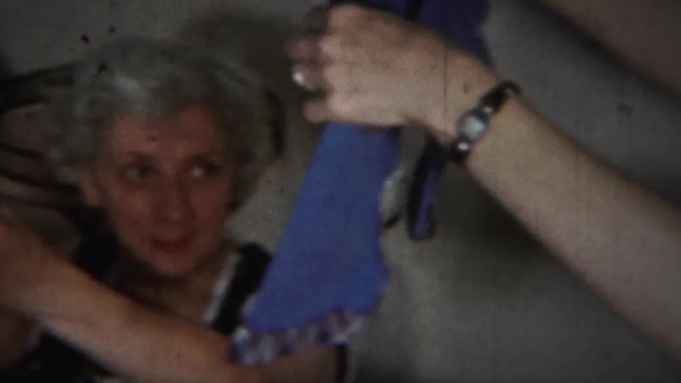 Westville 1951 home-movie frame with a light-haired woman seated near a hand holding a blue cloth, likely related to the baby scene.