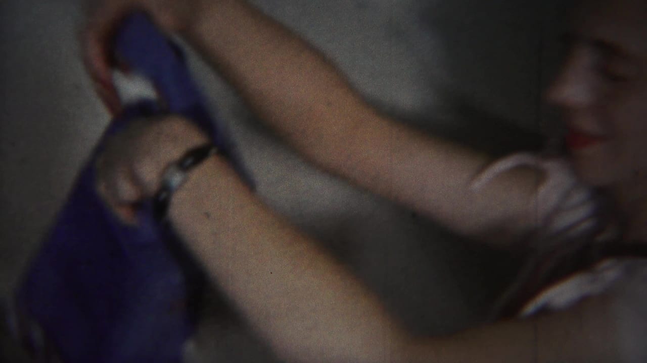Woman raises a blue garment while seated in a dim room.