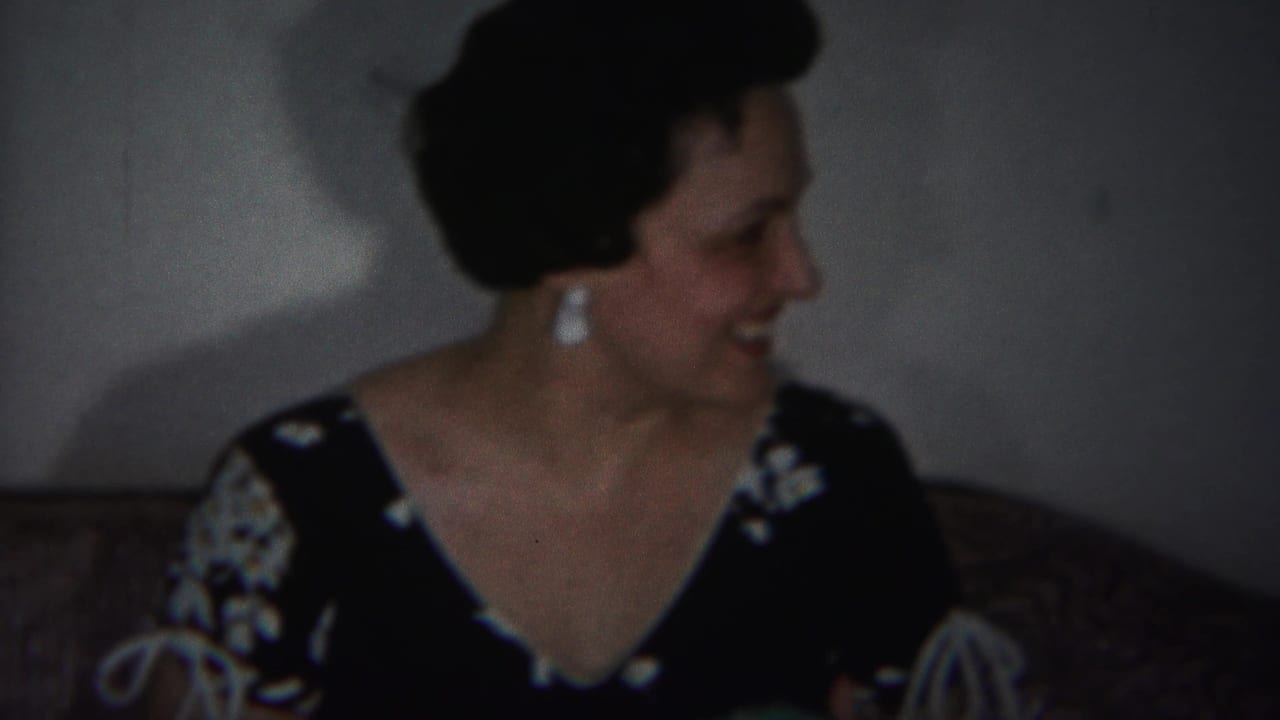 Woman seated on a couch turns her head to the right and smiles.