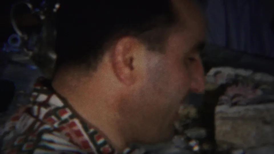 In 1951 Westville, New Jersey home-movie footage, a man in a patterned shirt sits close to a tabletop during conversation.