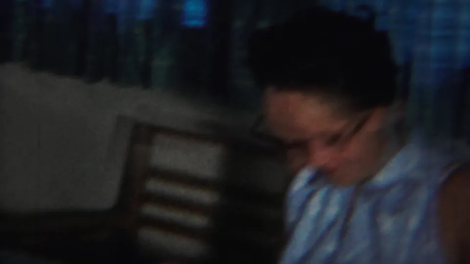 A woman in glasses, wearing a light sleeveless dress, looks down in a dim 1951 Westville home interior.