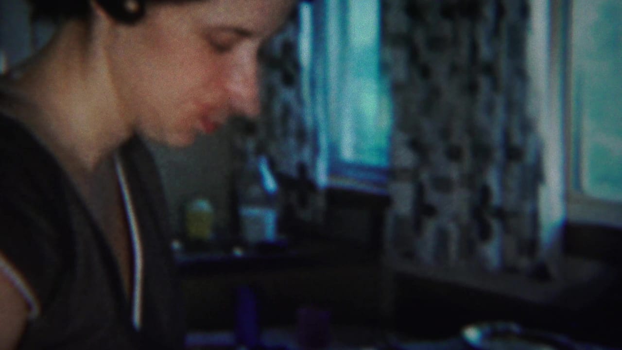 Woman in a dark dress leans down near a kitchen counter.