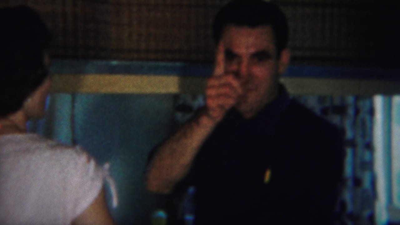 Man faces the camera area while raising one finger beside a woman in the foreground.