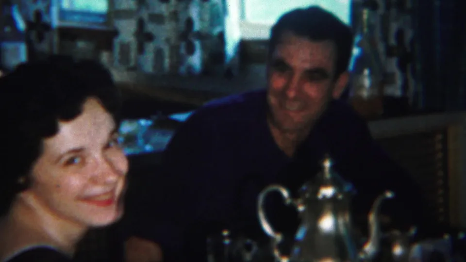 In this 1951 Westville, New Jersey home-movie frame, a woman smiles toward the camera while a man sits behind a silver teapot.