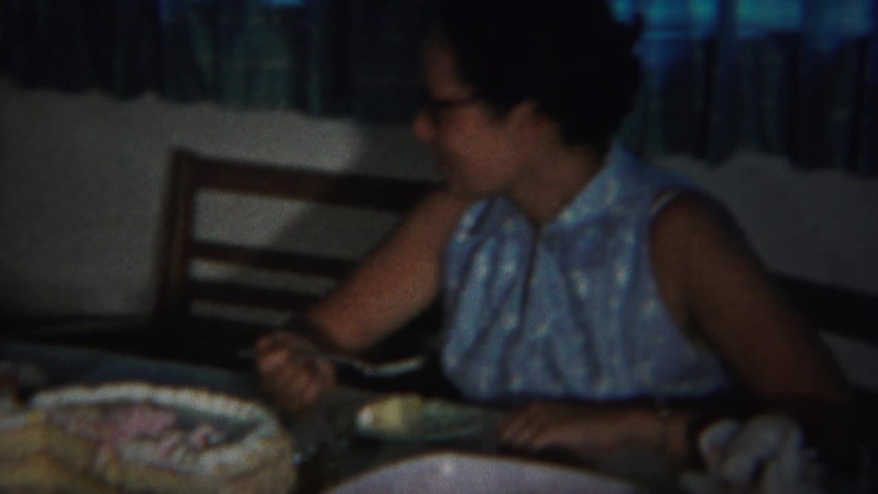 The woman turns in profile at a Westville home table, with a frosted cake, red bowl, dishes, and chair visible.