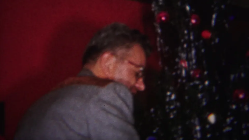 A bespectacled man turns near the Christmas tree during a 1951 home-movie holiday decorating moment in Westville.