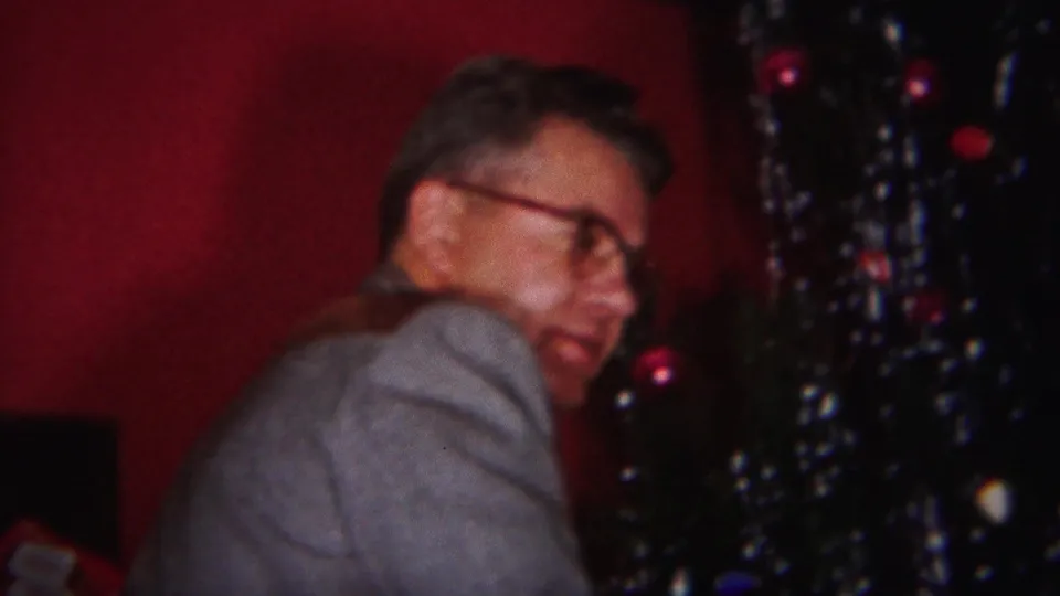 The man looks back toward the camera beside the ornamented Christmas tree in a Westville, New Jersey private interior.
