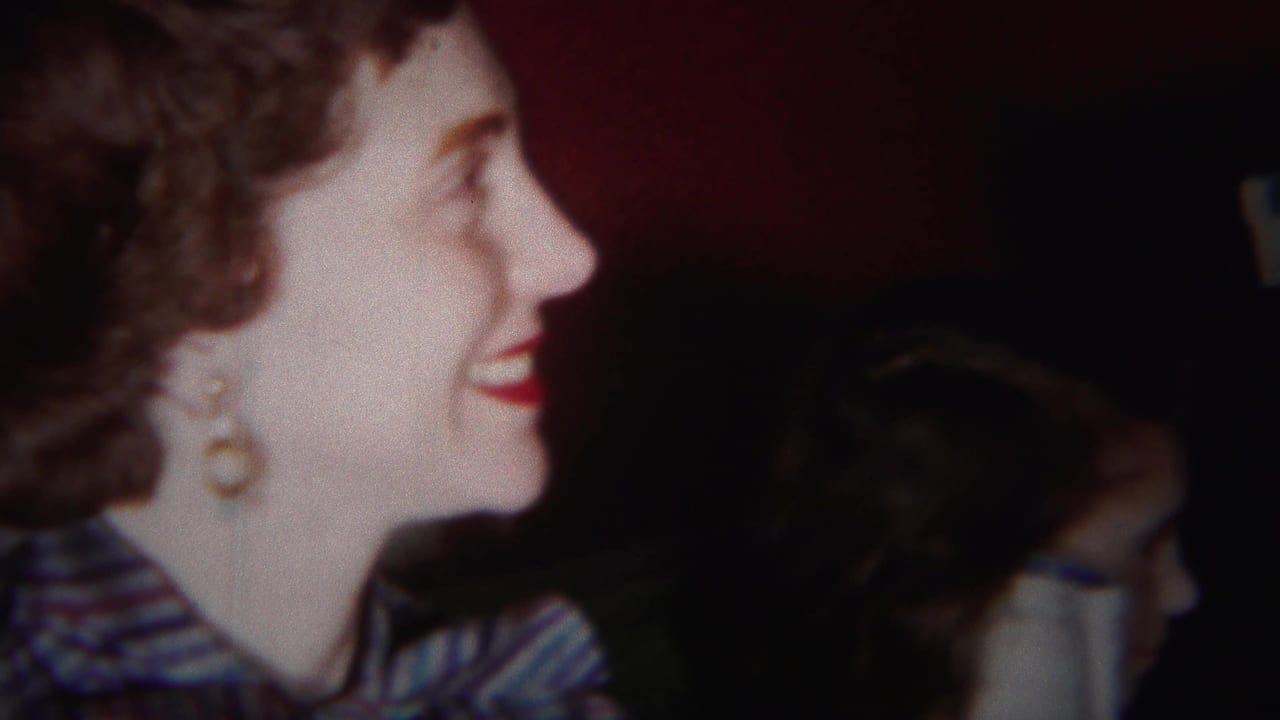 Woman in blue patterned dress smiles in profile beside a dim indoor background.