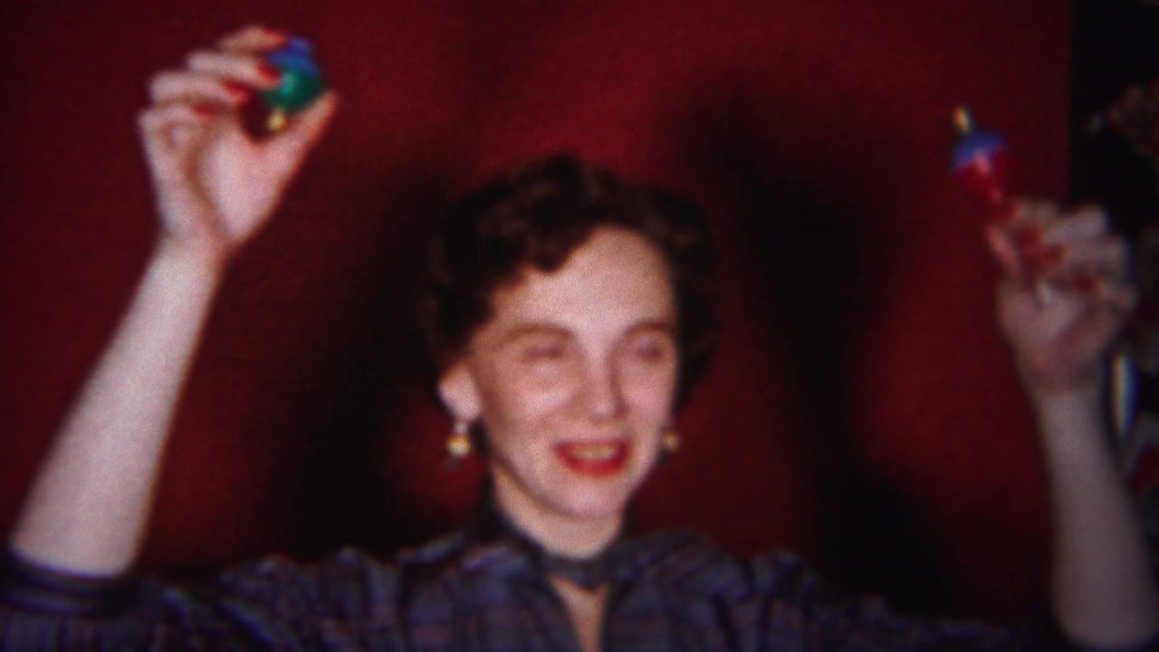 Woman in striped shirt raises her arms while holding a small colorful object.