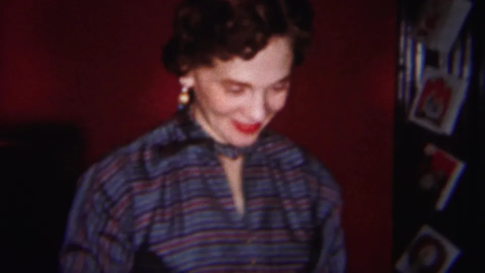 The woman remains in soft focus, smiling with her head lowered near small framed pictures in the Westville interior.
