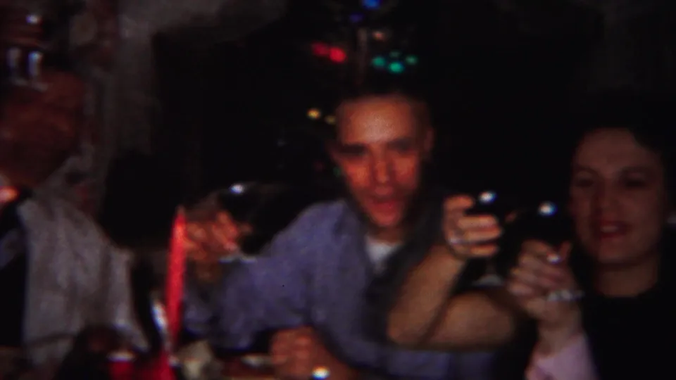 1951 Westville dinner-party frame with several adults seated close together, raising glasses beside a red candle on the table.