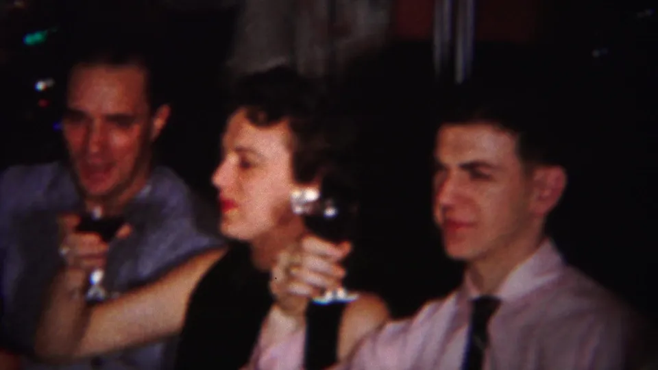 Westville, New Jersey home-movie frame showing adults in formal clothing holding glasses during a close indoor toast.
