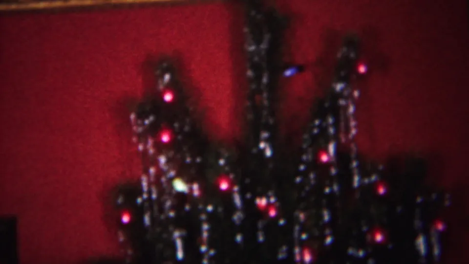 1951 Westville, New Jersey 8mm frame showing a decorated Christmas tree with tinsel, red lights, and a deep red backdrop.