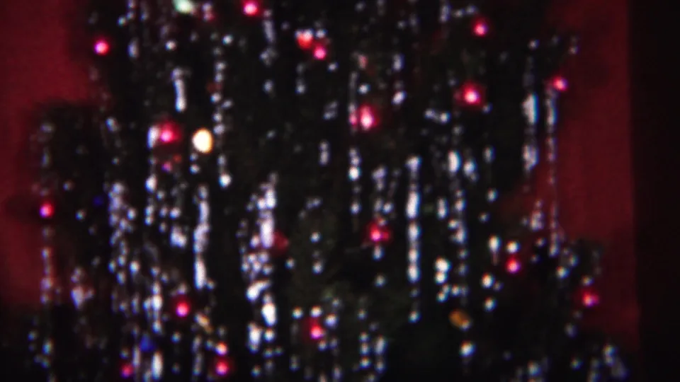 1951 Westville 8mm frame showing dense tinsel, dark evergreen branches, and small glowing bulbs on a Christmas tree.