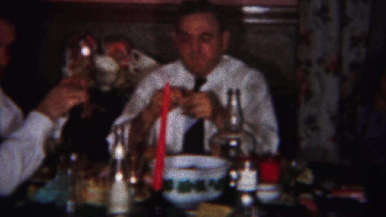 Men in white shirts sit at a dinner table with bottles and glassware.