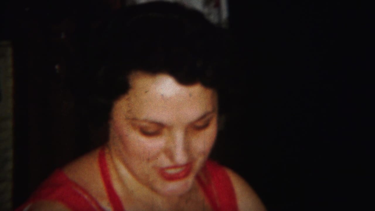 Adult woman in a red dress looks downward against a dark background.