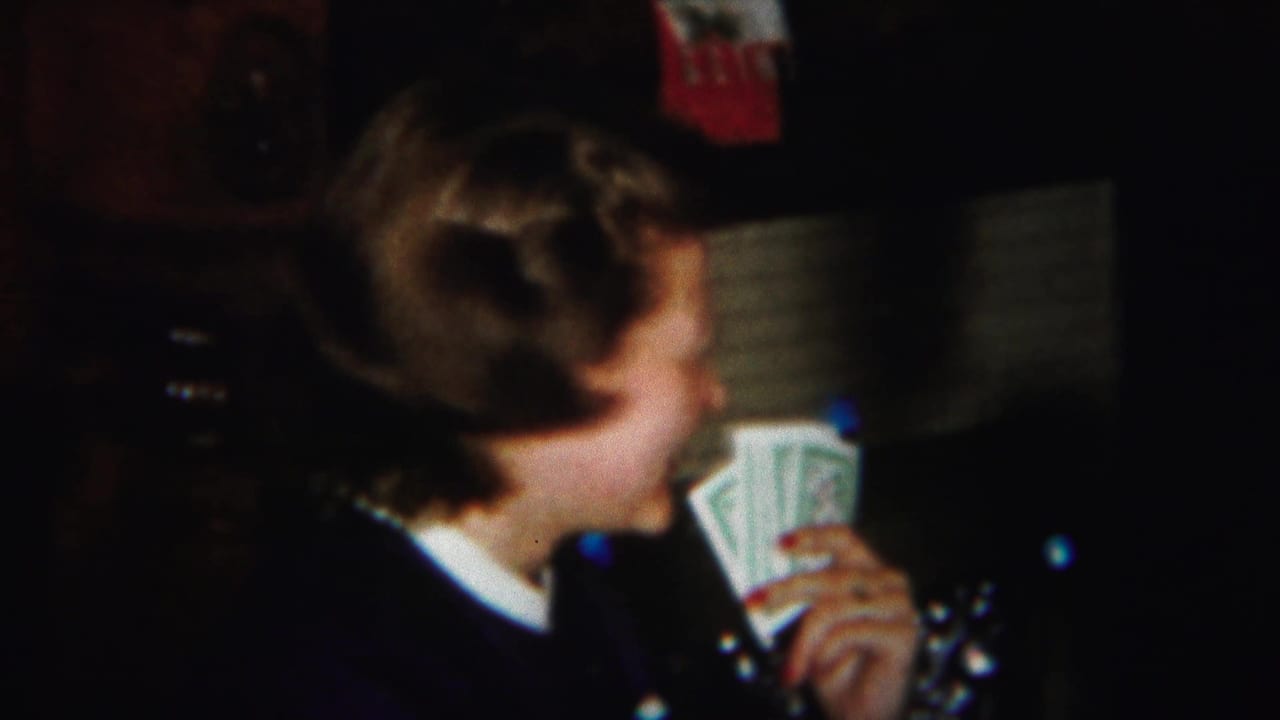 Woman in a dark sweater holds playing cards in a dim room.