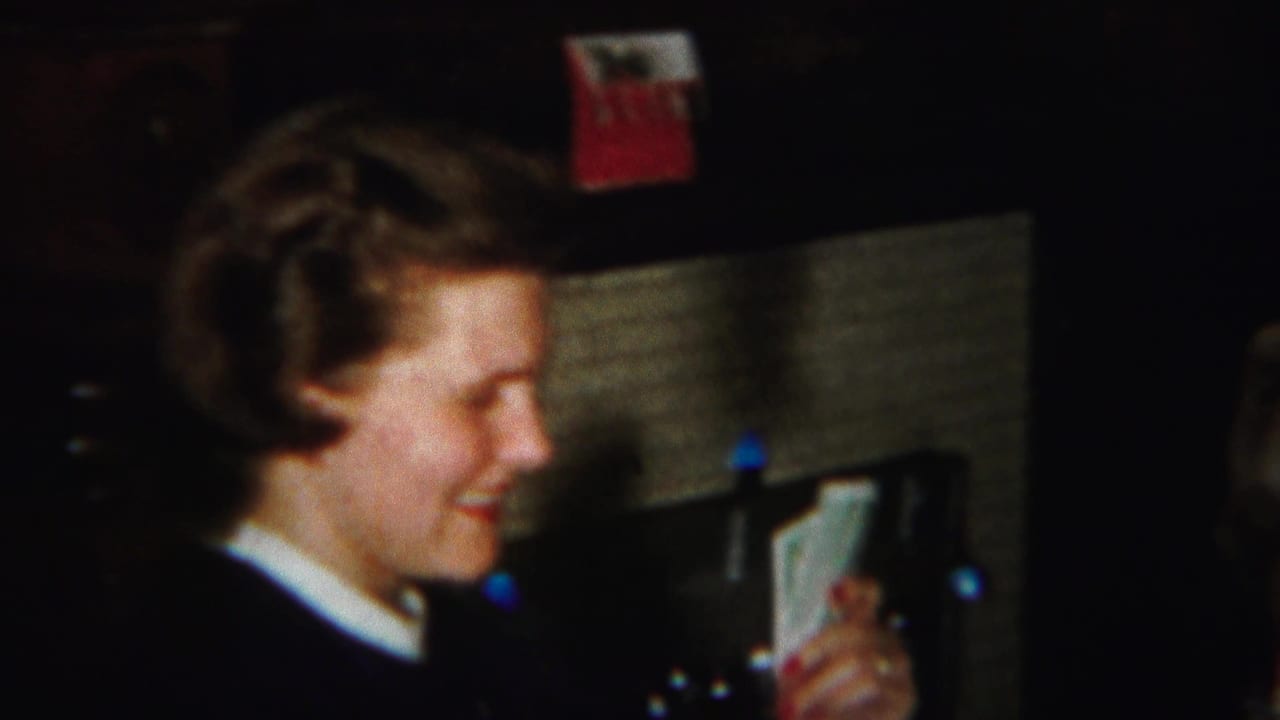 A woman with curled hair smiles over a hand of cards in this warm 1951 Westville home-movie frame.