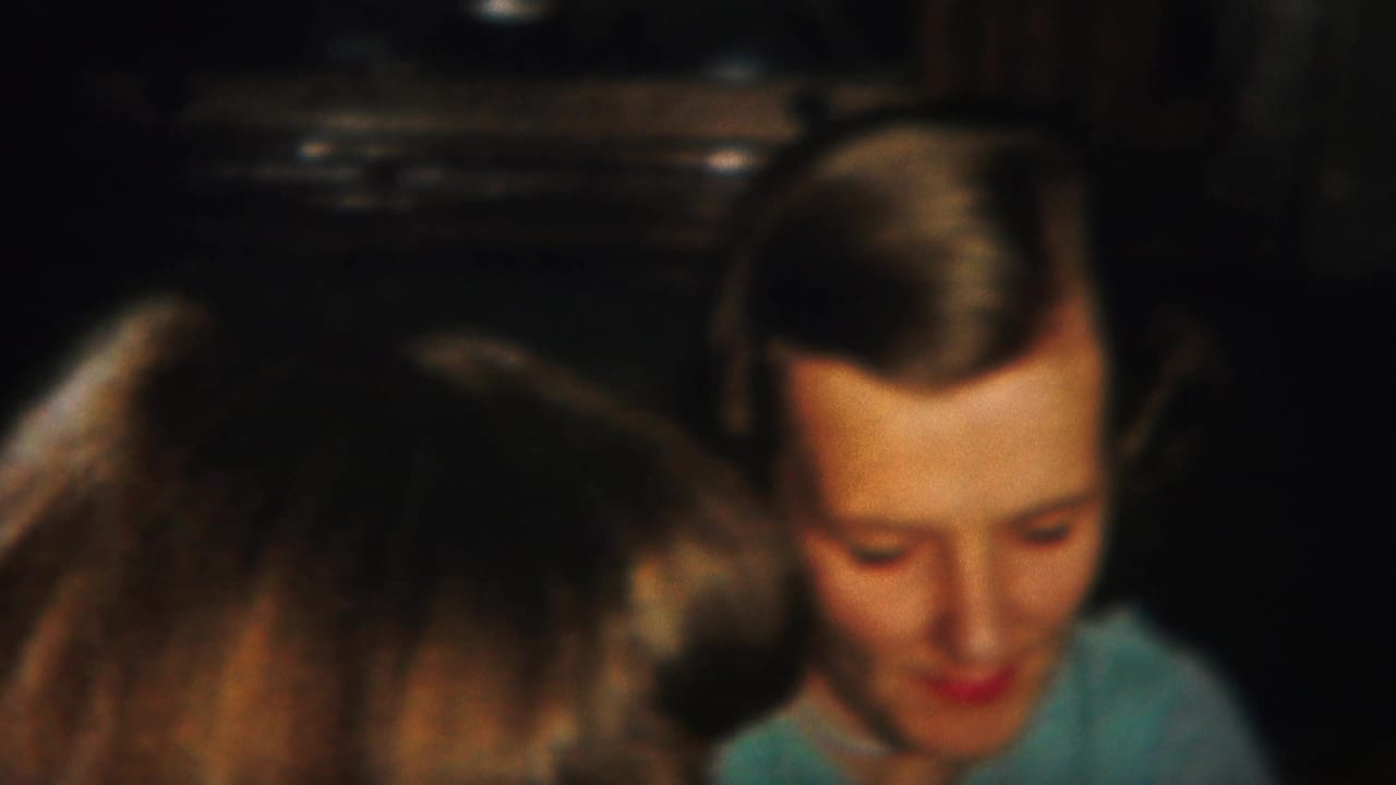 Two women with styled hair sit indoors while foreground heads partly block the view.