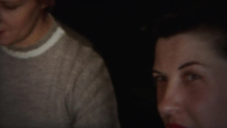 A cropped 8mm frame shows the woman's lower face, white collar, and gray sweater along the left side of the image.