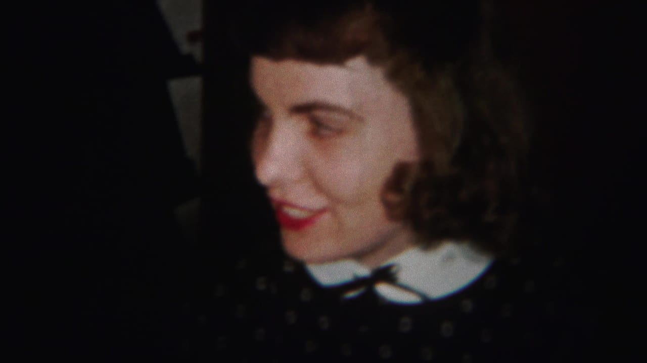 Woman in a dark polka-dot dress smiles in profile against a dark background.