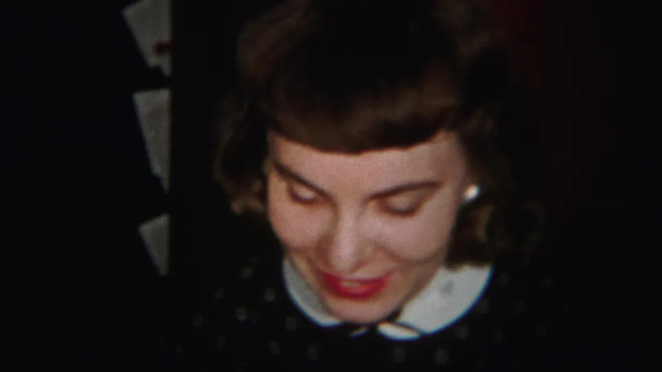 In 1951 Westville, New Jersey home-movie footage, a young woman in a dark polka dot dress with a white collar smiles while looking down.