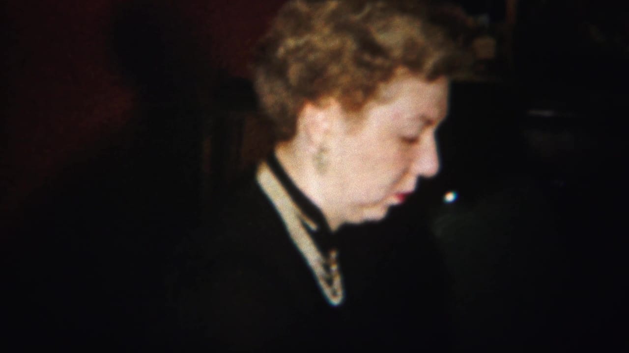 Woman in profile with curled blonde hair in a dim interior.