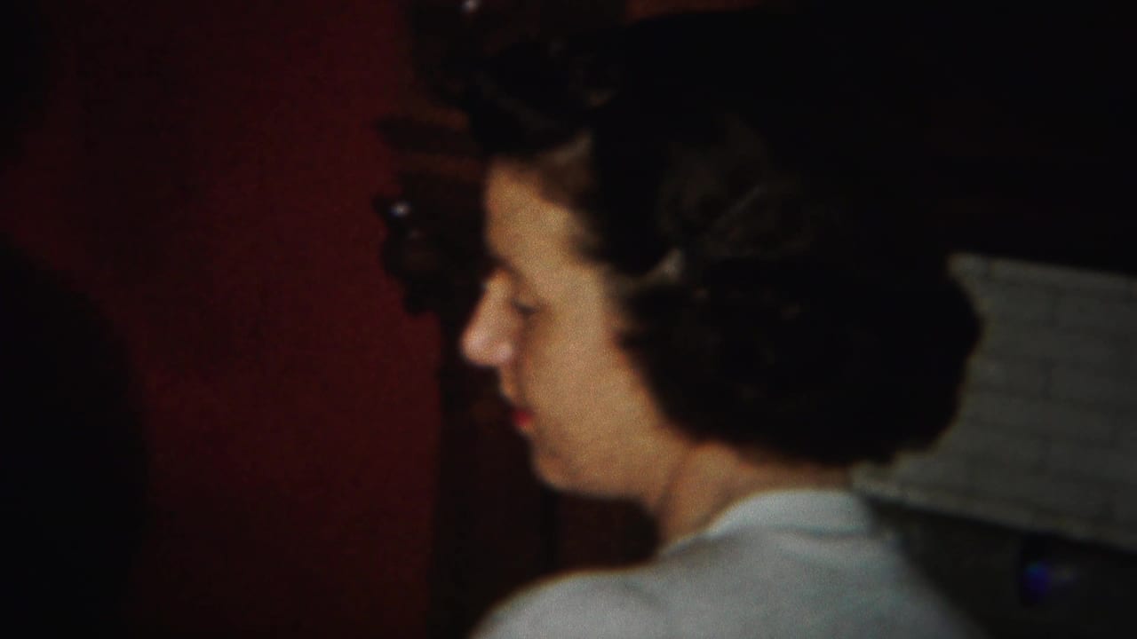 Two women in profile seated in a dim red-walled room.
