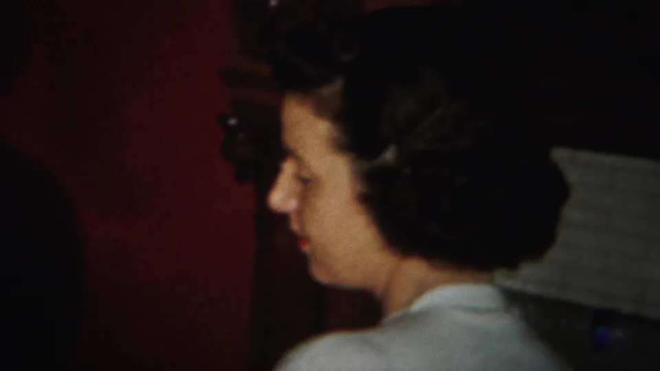 1951 Westville home-movie frame showing two women in profile inside a dim room with red walls.