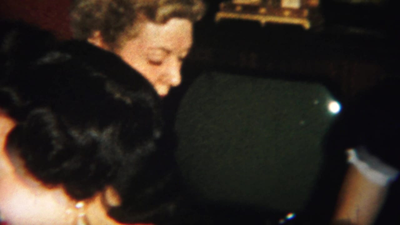 Several women lean close together around a card table, partly obscured by chair backs.