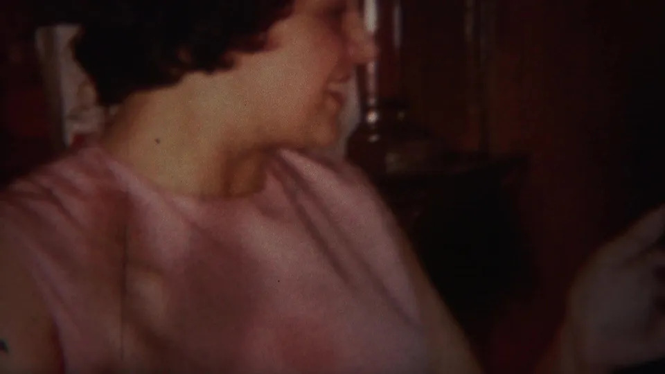 The woman turns her head in a 1951 Westville home interior, with wood cabinetry and a partial figure at the edge of frame.