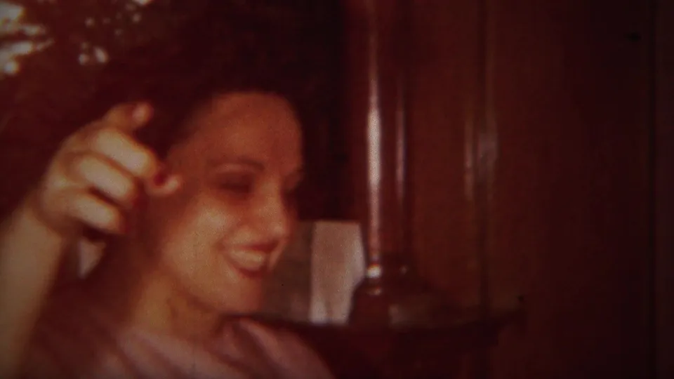 A woman smiles and gestures with one hand inside a Westville, New Jersey home, seen in warm 1951 8mm color.