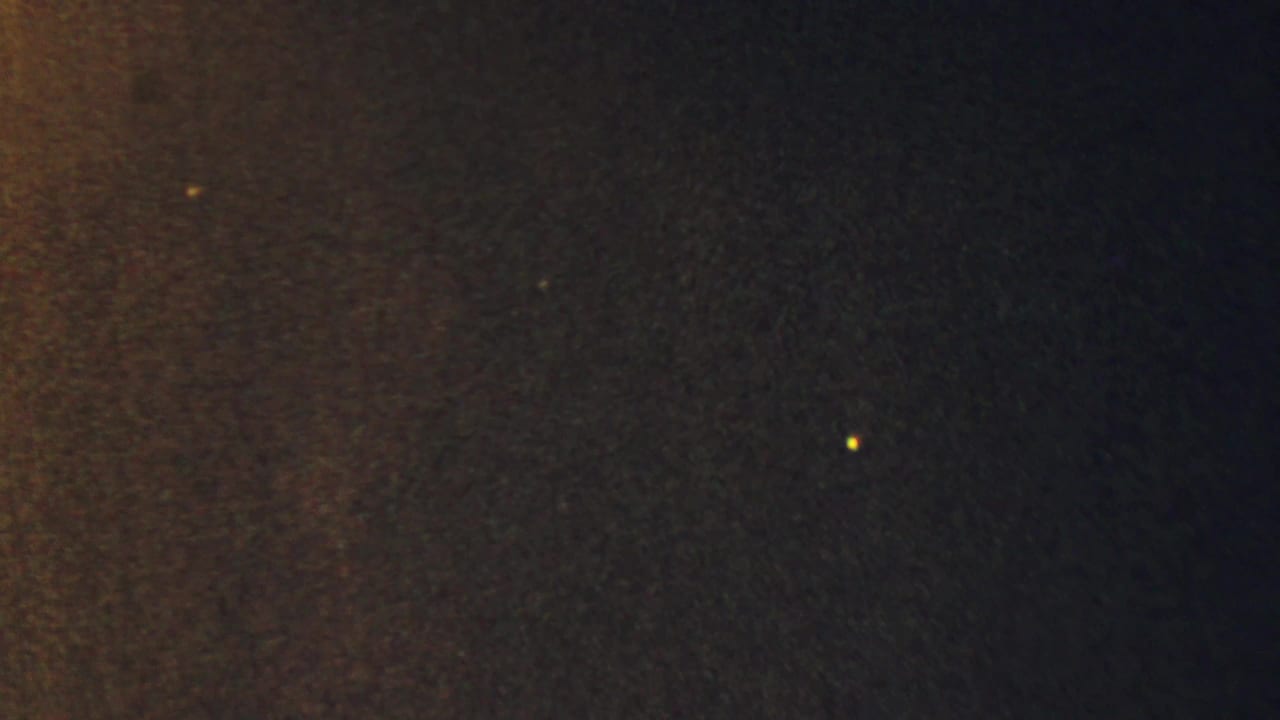 Mottled dark film surface with warm exposure and small bright specks.