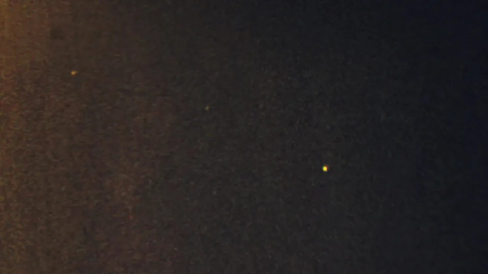 Abstract 8mm frame from the supplied 1959 Paramus reel, with warm brown texture, dark blue-black areas, and tiny light specks.