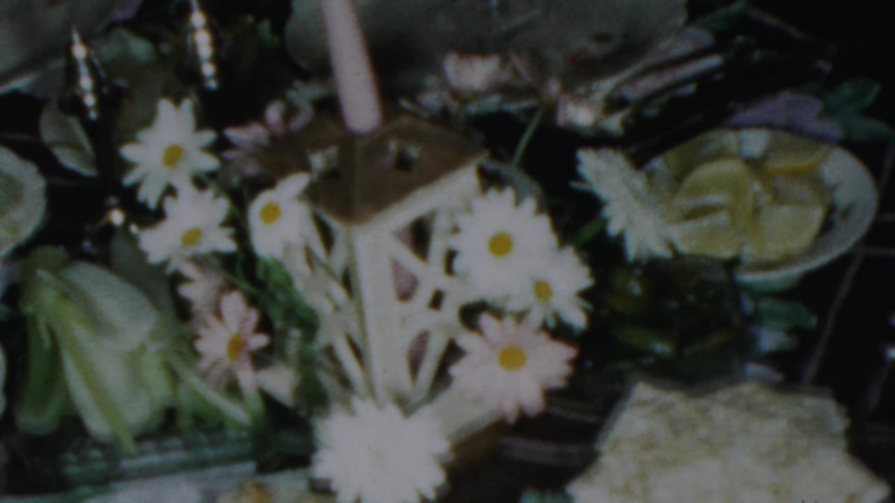 1959 Paramus holiday table detail with daisies around a small candle lantern, white dishes, green fruit, and a pale serving bowl.