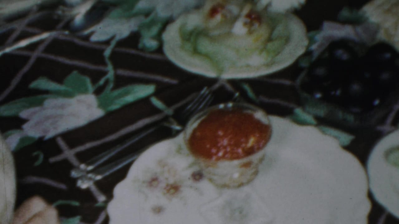 1959 Paramus holiday dinner detail showing a plated cake or pastry, forks, white dishes, dark fruit, and part of the decorated table.
