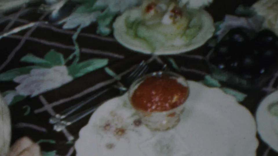 1959 Paramus holiday dinner detail showing a plated cake or pastry, forks, white dishes, dark fruit, and part of the decorated table.