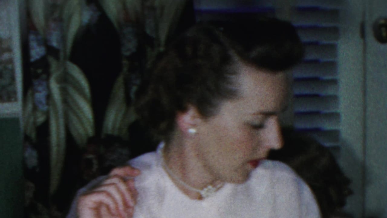 A woman in a white blouse, pearl necklace, and styled hair appears beside the holiday table in a private Paramus home interior.