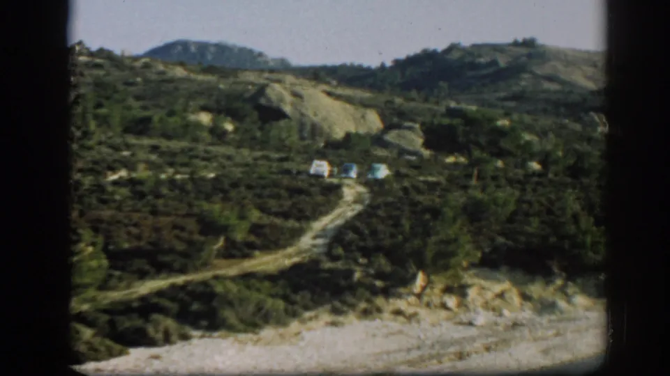 A 1962 Ephesus-area travel view shows three parked cars on a rough road through scrubby hills.