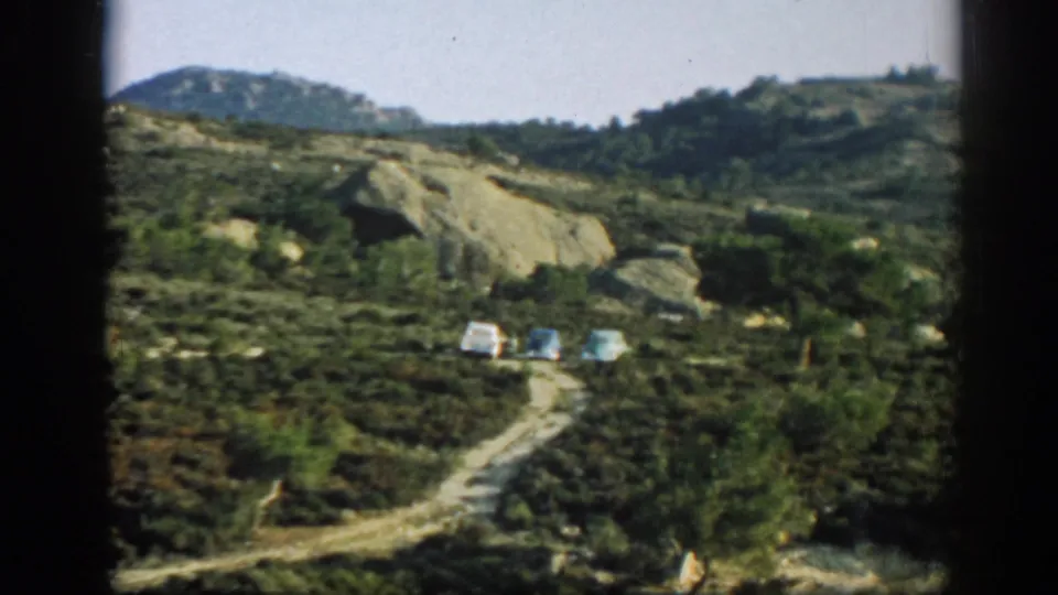 Three cars are parked on a mountain road in 1962 home-movie footage identified as near Ephesus, Turkey.