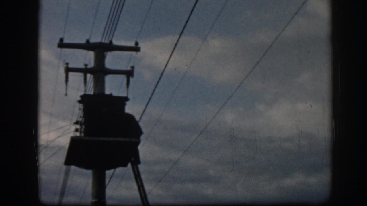 Utility pole with crossarms and diagonal wires silhouetted in the sky.