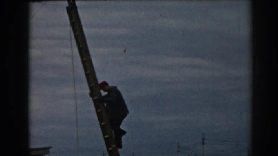 A worker climbs the ladder near wires in the 1962 Ephesus, Turkey clip, with distant utility poles faintly visible below.