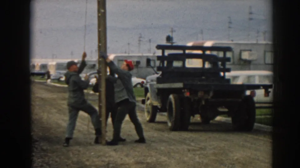 Near the end of the clip, the men hold the wooden pole upright in the Ephesus trailer yard with the truck and trailers behind them.
