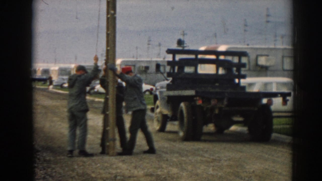 Three men in work clothes, including one wearing a red cap, reposition a wooden pole at a roadside location in Ephesus, Turkey, according to the clip metadata.