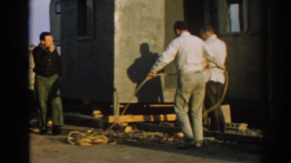 Adult men in Ephesus, Turkey work with a coiled rope near a raised portable structure in bright 1962 daylight.