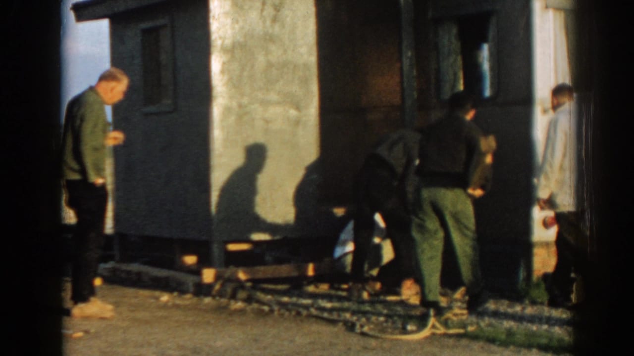 A small group continues work beside the building in Ephesus, Turkey, with a crouching man, standing figures, materials, and a wall shadow visible.